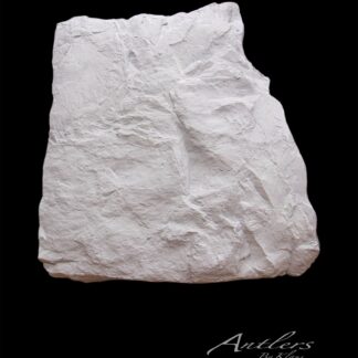 A flat, irregularly shaped white Reproduction Rock with a rough texture is displayed on a solid black background. “Antlers By Klaus” is written in script in the lower right corner.