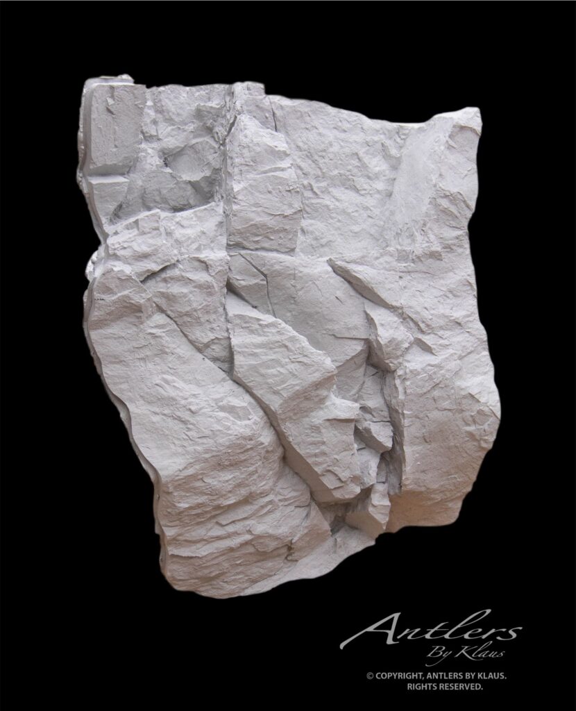 A jagged, light-gray Reproduction Rock with layered, uneven surfaces is set against a solid black background. “Antlers by Klaus” is written in cursive at the bottom right corner.
