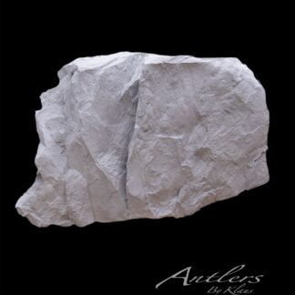 A large, light-gray Reproduction Rock with rough, textured surfaces stands against a solid black background. The words “Antlers By Klaus” are written in white cursive at the bottom right.